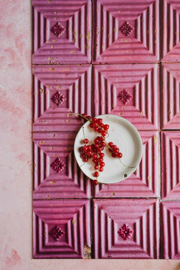 biały talerz z czerwonymi porzeczkami na tle różowych kafelków azulejos