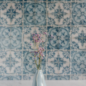 niebieski wazon z kolorową gipsówką na tle niebieskich kafelków azulejos