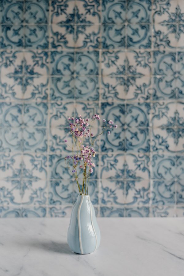 niebieski wazon z kolorową gipsówką na tle niebieskich kafelków azulejos