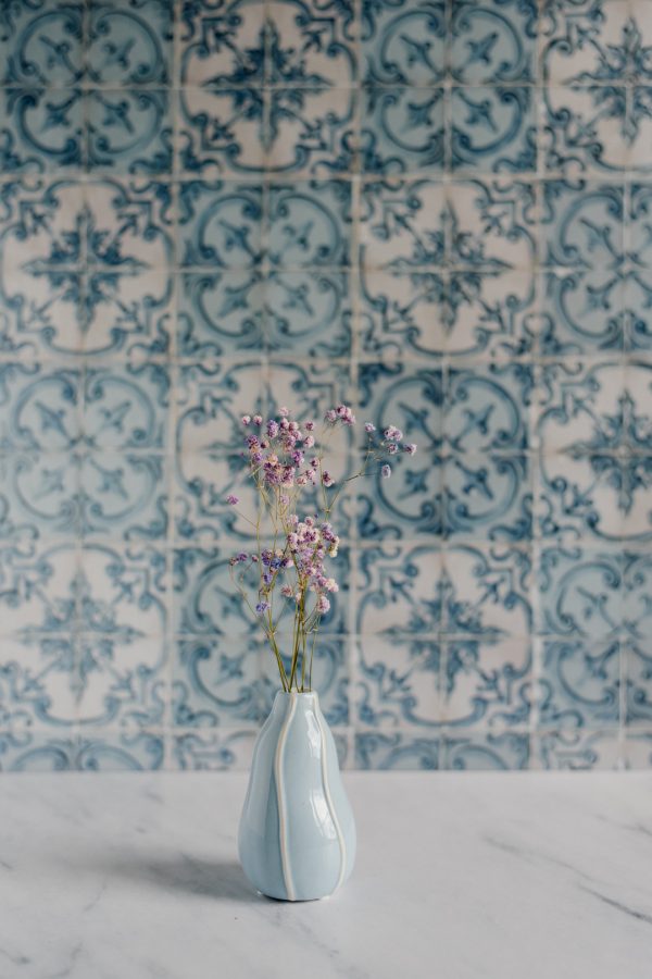 niebieski wazon z kolorową gipsówką na tle niebieskich kafelków azulejos