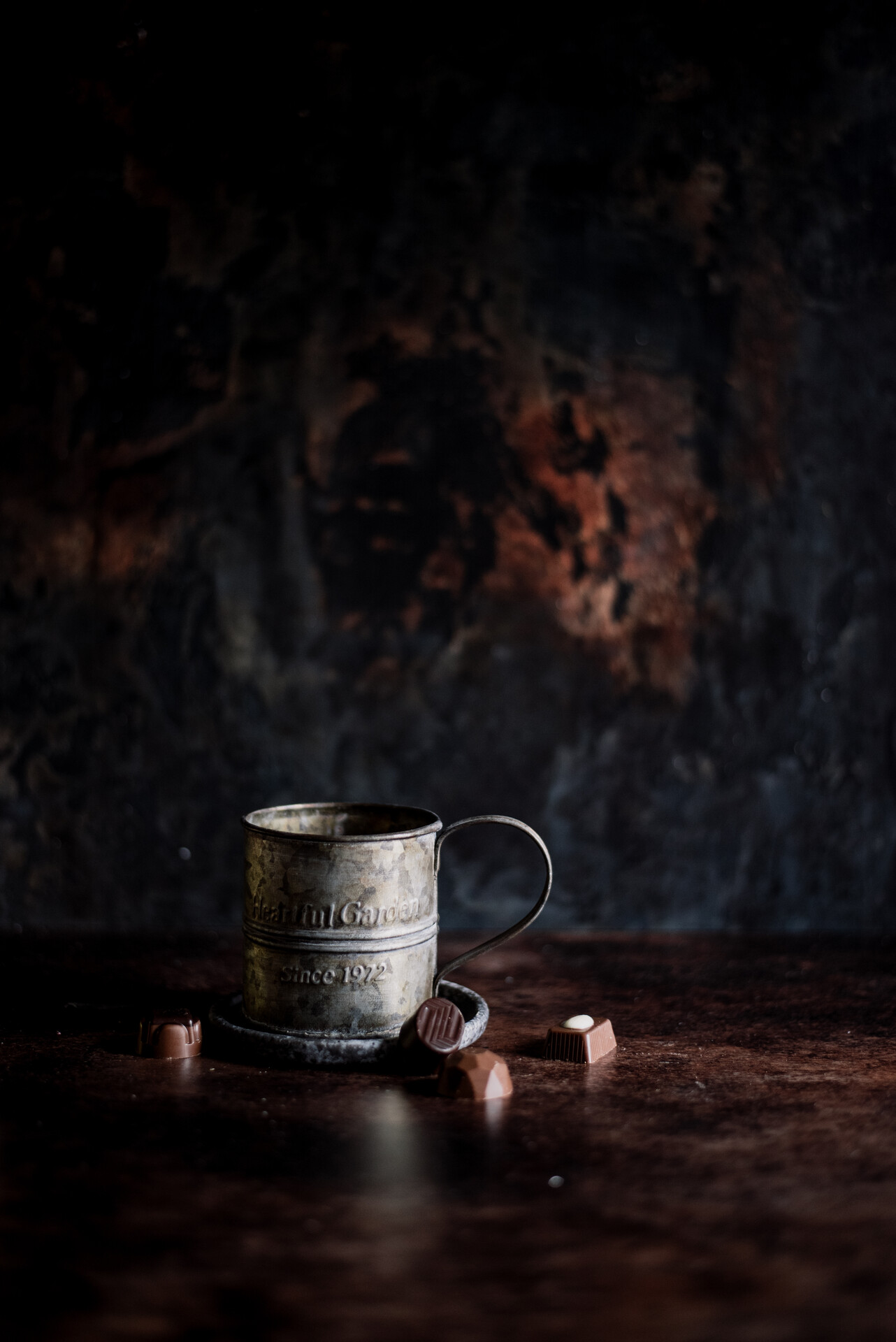 metalowy kubek z pralinami na ciemnym tle.