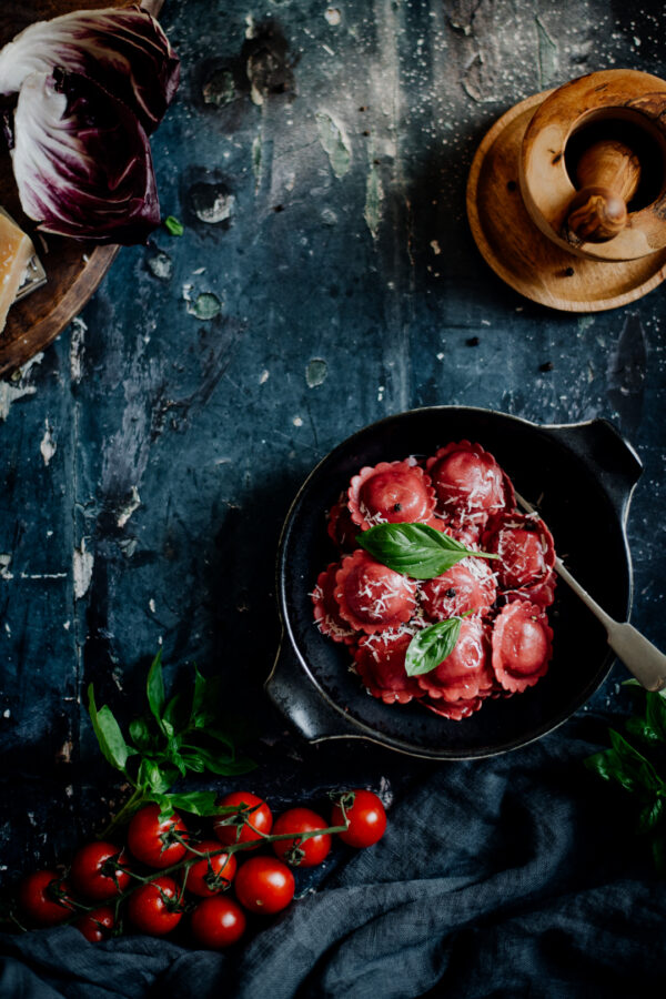 Zdjęcie kulinarne z włoskimi ravioli na drewnianym, ciemny tle, w stylu dark mood.