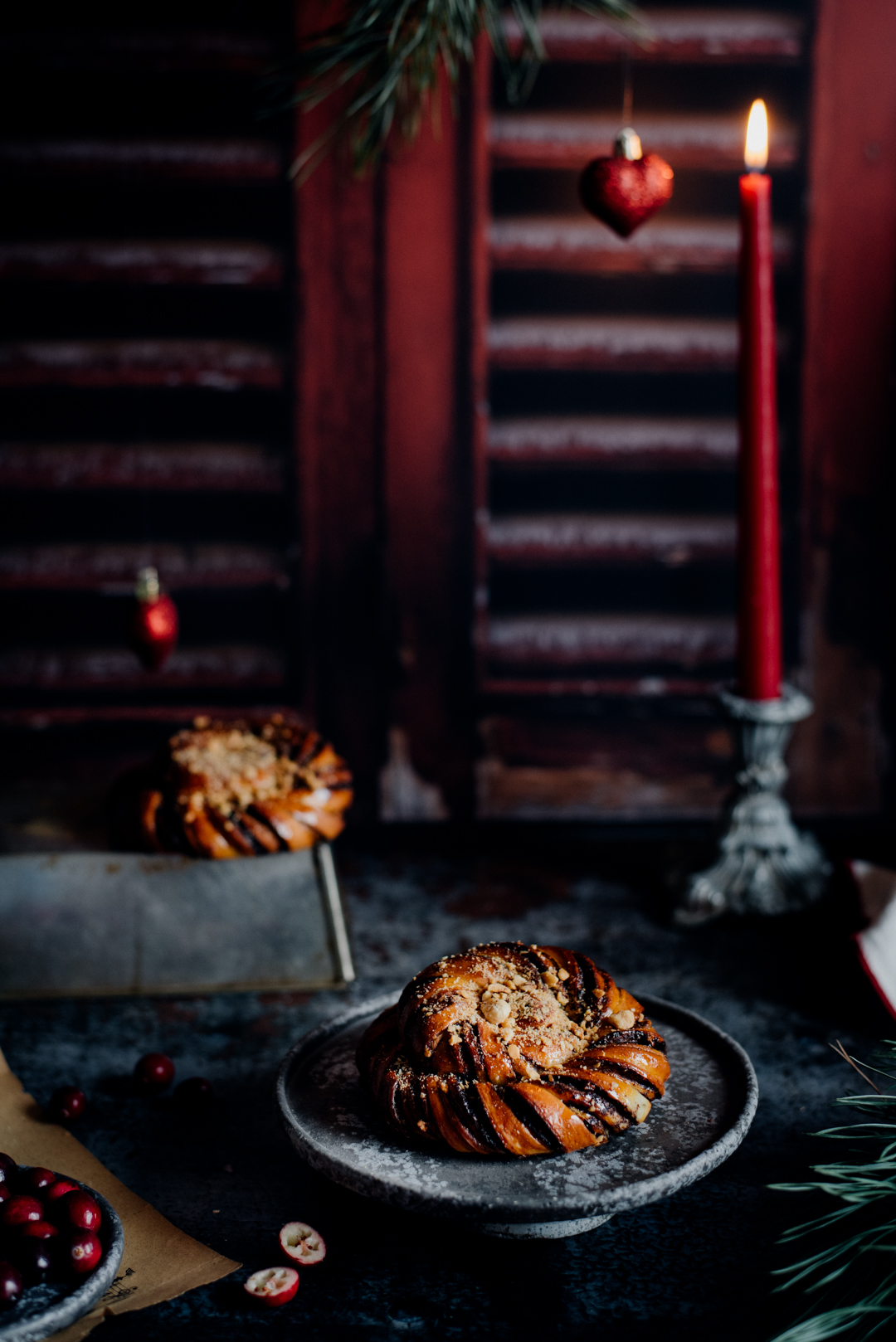 świąteczna stylizacje cynamonek na tle brązowych, drewnianych żaluzji z płonącą czerwoną świecą.