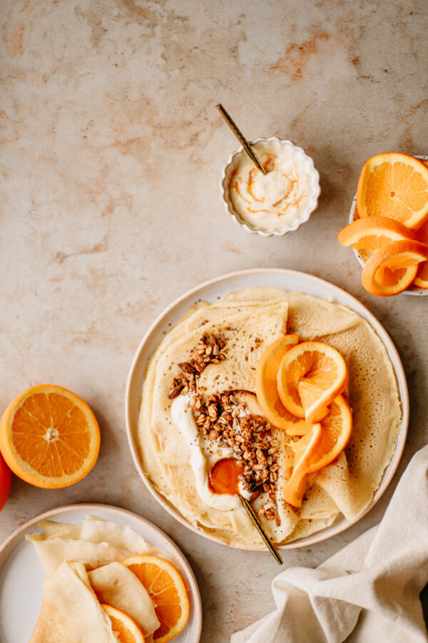 Naleśniki z jogurtem, granolą i plasterkami pomarańczy sfotografowane na jasnym, neutralnym tle fotograficznym MBackdrops