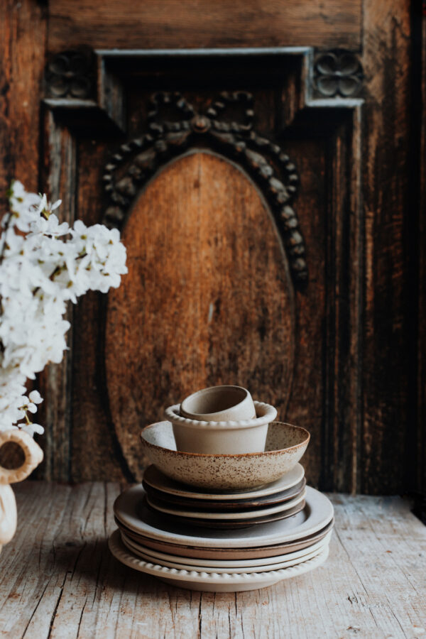 Tło fotograficzne Portone — ciemne rzeźbione drzwi z ceramiką rzemieślniczą i białymi kwiatami — mbackdrops