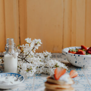 Tło fotograficzne Limone — kremowe drewniane drzwi z pancakes, truskawkami i kwiatami wiśni — mbackdrops
