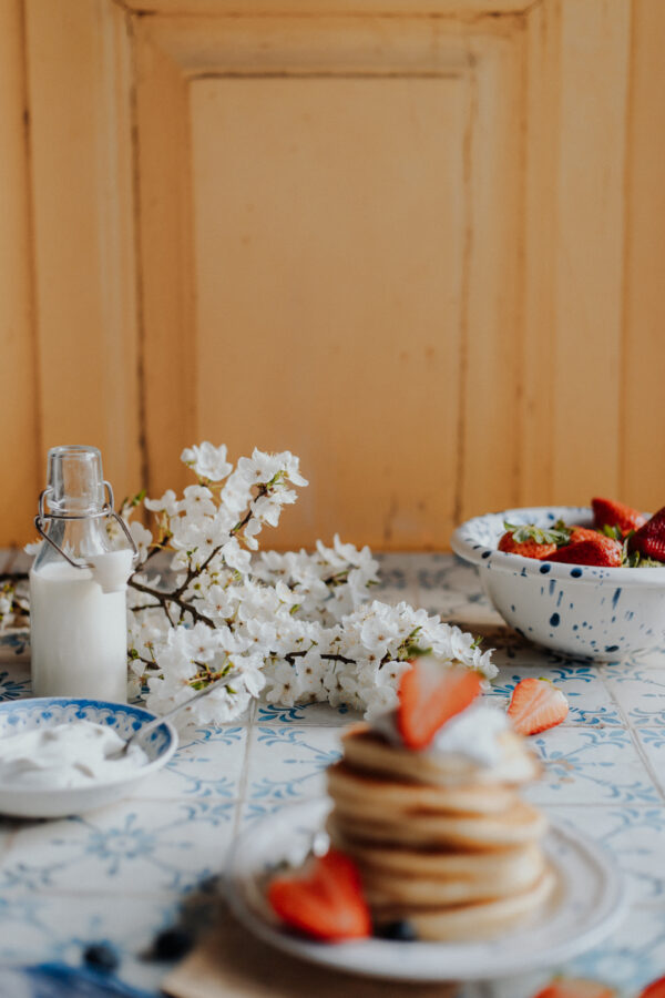 Tło fotograficzne Limone — kremowe drewniane drzwi z pancakes, truskawkami i kwiatami wiśni — mbackdrops