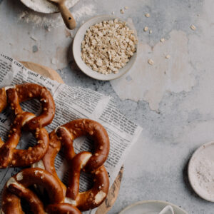 Tło fotograficzne Grigio — jasny beton z preclami na desce i ceramiką, flat lay kulinarny — mbackdrops