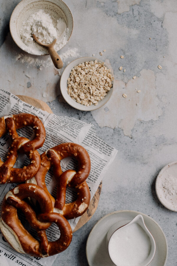 Tło fotograficzne Grigio — jasny beton z preclami na desce i ceramiką, flat lay kulinarny — mbackdrops